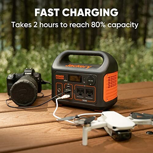 Portable power station charging a camera and drone outdoors.